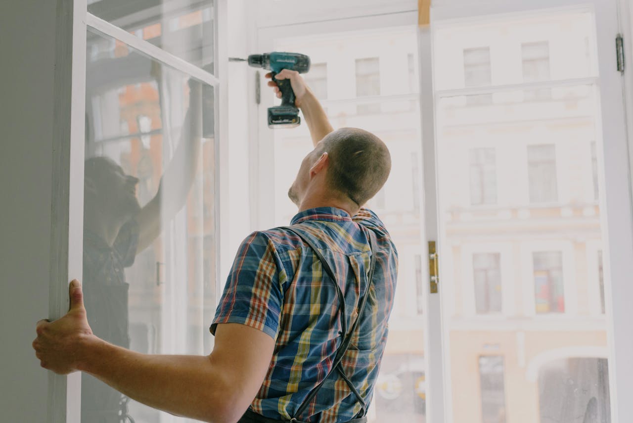 A man in a checked shirt fitting a window